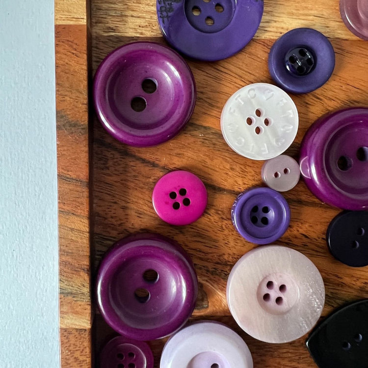 wood tray with various vintage purple buttons in different shades of purple