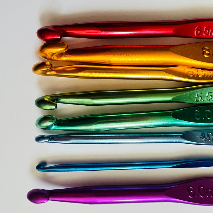 rainbow crochet hooks lined up on the right hand side in horizontal rows, bright aluminium