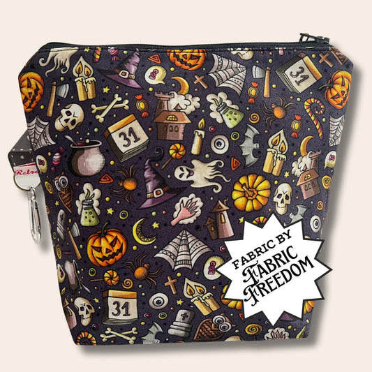 A dark grey bag covered in cartoon Halloween illustrations. A foreground banner reads "Fabric by Fabric Freedom"